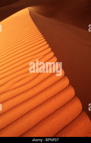 La arena que sopla desde la cresta de una duna de Erg Chebbi, cerca de Merzouga en Marruecos Foto de stock