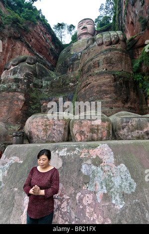 Mujer ora delante del gigante de dedos del Dafo o Gran Buda, Le Shan, en la provincia de Sichuan, China