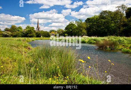 Vista de verano a través de pradera y río Windrush a San Juan Bautista, Iglesia en la ciudad de Cotswold de Burford, Oxfordshire, Inglaterra, Reino Unido.