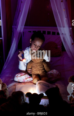 Niña leyendo a sus osos de peluche en la noche Foto de stock