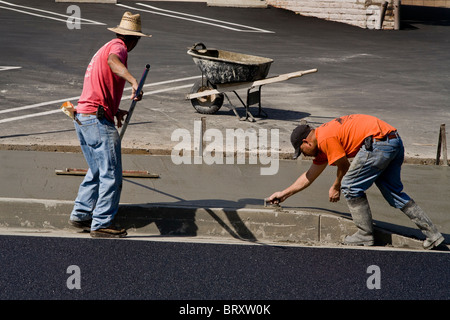 Los obreros hispanos vistiendo camisetas de seguridad de alta visibilidad acera de cemento fresco suave en una calle de Laguna Niguel, CA. Foto de stock