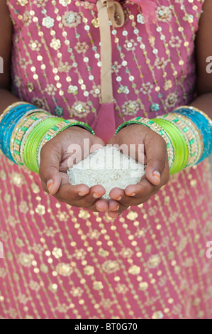 Niña india celebración arroz crudo en sus manos ahuecados. La India