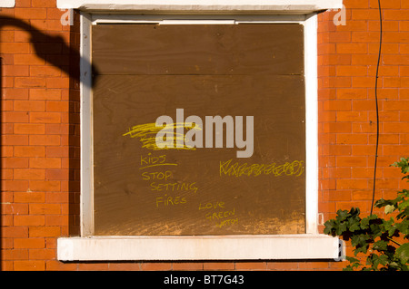 Mensaje escrito en un clausurado abandonada vivienda adosada en espera de demolición en la Clayton, en el distrito de Manchester, Inglaterra, Reino Unido. Foto de stock