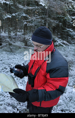 Caminante verificando el curso con un mapa y un receptor GPS cerca de Filipstad en invierno, Vaermlands Lan, Suecia Foto de stock