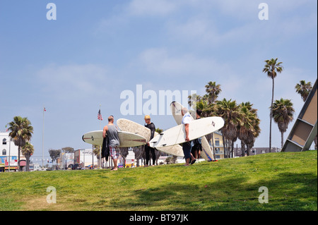 Grupo de surfistas dejando llevar tablas de surf, la playa de Venice Beach, Los Angeles, California, Estados Unidos. Apartar la mirada de la cámara