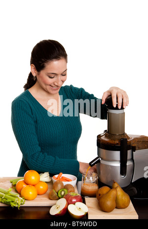 Bella mujer en la cocina haciendo zumo recién exprimido orgánica utilizando una licuadora, aislado. Foto de stock