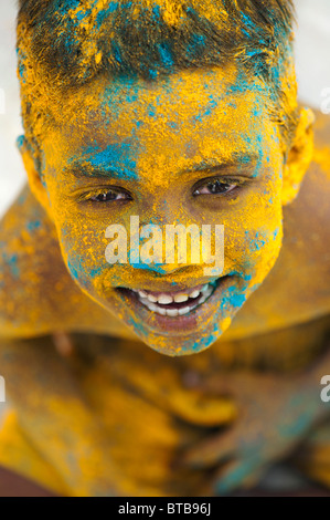 Feliz joven niño indio cubierto de polvo coloreado. La India