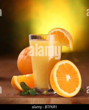 Still life: naranjas y vaso de jugo en una mesa de madera. Foto de stock