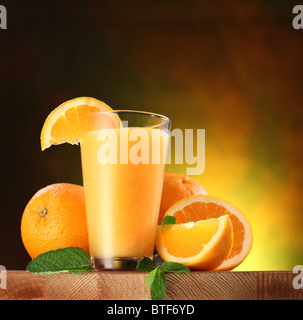 Still life: naranjas y vaso de jugo en una mesa de madera. Foto de stock