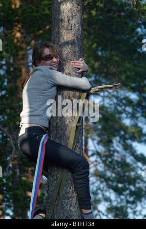 La joven se subió a un árbol y sentóse estrechando manos Foto de stock