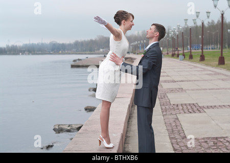 Hermosa joven recién casada pareja caminando por el muelle de Petrozavodsk, Rusia. Abrazándose entre otros