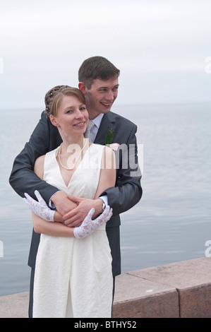 Hermosa joven recién casada pareja caminando por el muelle de Petrozavodsk, Rusia. Abrazándose entre otros