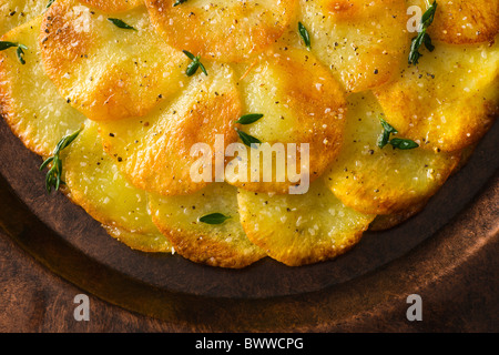 Tortas de patata o Anna aderezado con tomillo fresco, sal y pimienta y se sirve en un plato rústico.