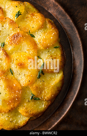 Tortas de patata o Anna aderezado con tomillo fresco, sal y pimienta y se sirve en un plato rústico.