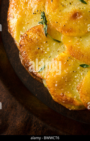 Tortas de patata o Anna aderezado con tomillo fresco, sal y pimienta y se sirve en un plato rústico.