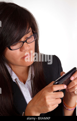 Adolescente con gafas en un traje de negocios texting en un iPhone contra un fondo blanco. Foto de stock