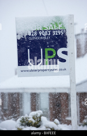 Los agentes inmobiliarios firmar recubiertas de nieve en inviernos fríos con nieve día en Belfast, Irlanda del Norte