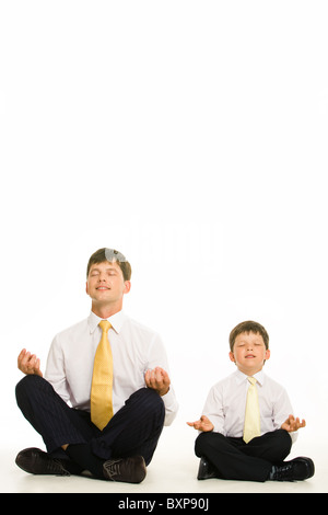 Imagen del hombre y el muchacho meditando en studio sobre fondo blanco. Foto de stock