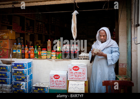 Comerciante de la calle local de pie en escaparates con el bloc de notas, Luxor, Egipto, África