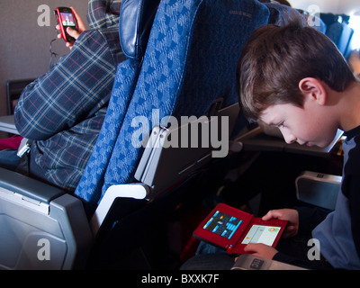 Niño jugando Nintendo DS en el plano Foto de stock