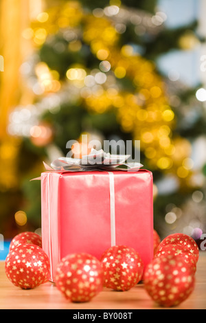 Imagen de la caja de regalo roja rodeado por varias pelotas de juguete sobre fondo brillante