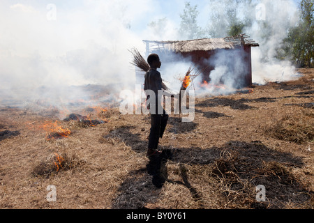 MUECATE distrito cerca de Nampula, Mozambique, en mayo de 2010 : un trabajador agrícola se quema de rastrojo y hierba en una granja. Foto de stock