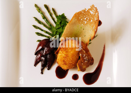 Hígado de pato asado con huevo cocido, espárragos trigueros y cebolla confitada rojo servido en una placa blanca, alimentos, haute cuisine Foto de stock