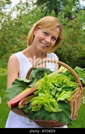 Mujer joven sosteniendo una cesta con verduras