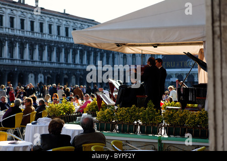 Los músicos tocando en un Café al aire libre, la Plaza de San Marcos, en Venecia, Italia Foto de stock