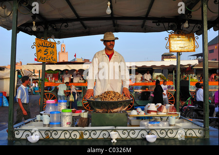 Hombre vendiendo caracoles cocidos en agua de un calado en la Djema el Fna en Marrakech, Marruecos, África Foto de stock