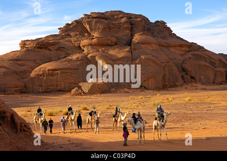 Turistas aventureros con dromedarios en una excursión en las montañas Acacus, el desierto del Sahara, Libia Foto de stock
