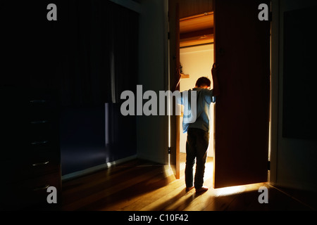 Boy se encuentra en puertas de armarios iluminados desde dentro