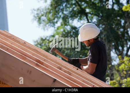 Carpintero martillando sobre las vigas del techo