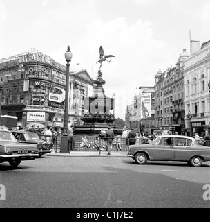 Los años sesenta, los coches de la época que rodean la famosa estatua de Eros en la rotonda de tráfico en Piccadilly Circus, Westminster, Londres, Inglaterra, Reino Unido. Foto de stock