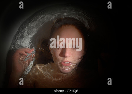 Una joven mujer se hunde bajo el agua en el baño. Foto de stock