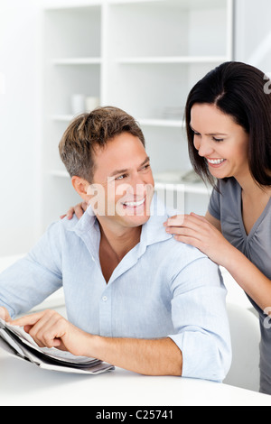 Hombre feliz mostrando algo en el periódico a su novia