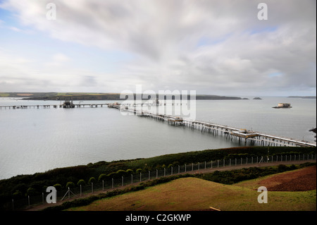 Vista desde Milford Haven en la bahía a la refinería de petróleo en Rhoscrowther, con la fortaleza de la roca de pila (derecha) Wales UK