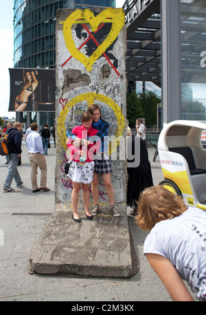 Los turistas posando delante de una parte del Muro de Berlín, Berlín, Alemania Foto de stock
