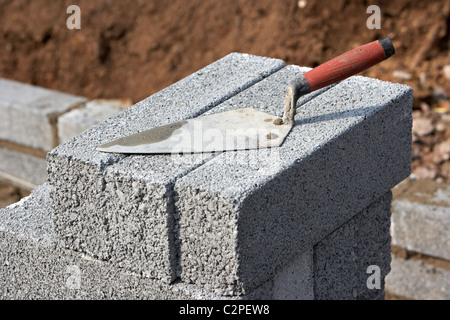 Alise bricklaying un montón de bloques de cemento media brisa la construcción de un muro de contención de bloque en el reino unido Foto de stock