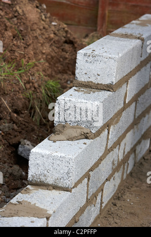 Con la mitad de la pared bricklaying brisa cemento bloquea la construcción de un muro de contención de bloque en el reino unido Foto de stock