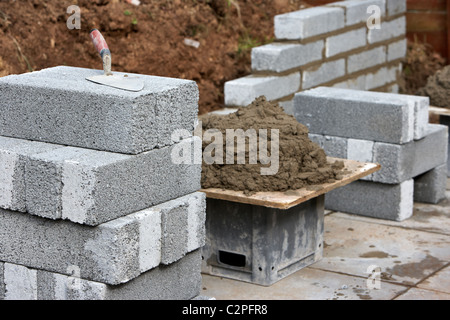 Con la mitad de la pared bricklaying brisa cemento bloquea la construcción de un muro de contención de bloque en el reino unido Foto de stock