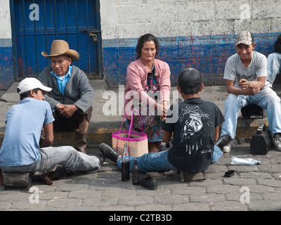 Un hombre mayor de edad tiene sus zapatos brilló en la acera mientras su esposa mira en Antigua, Guatemala. Foto de stock