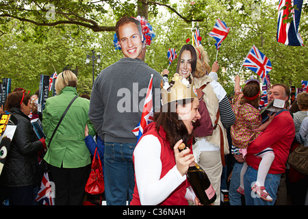Multitud celebra la boda real con cartoon cortar las caras del príncipe willim y Catherine el Duque y Duquesa de Cambridge.
