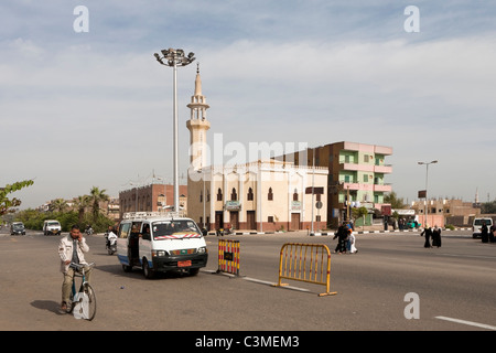 Panorama general de la calle, en Luxor, Egipto con taxi local y mina en bicicleta en teléfono móvil y minarete en segundo plano.