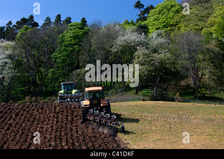 Los tractores que están arando los campos coloridos en primavera. Aberdeenshire, Escocia. Foto de stock