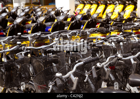 Bicicletas y motos scooter filas en un patrón de tienda de alquiler Foto de stock