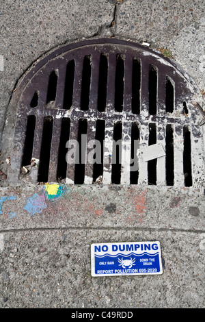 Ningún dumping únicamente por el desagüe de lluvia signo en San Francisco calle junto a la tapa de desagüe con salpicaduras de pintura Foto de stock