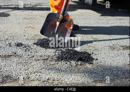 Los obreros la sustitución de daños en la superficie de la carretera con asfalto Foto de stock
