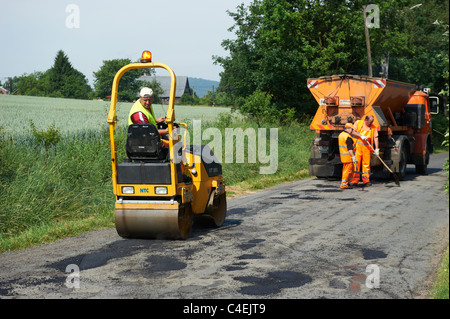 Los obreros la sustitución de daños en la superficie de la carretera con asfalto Foto de stock