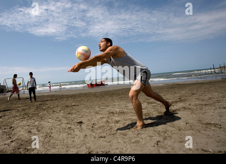 Grupo de amigos jugando voleibol en la playa, en el Mar Caspio en Bandar-e Anzali, Irán Foto de stock